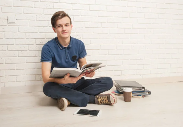 Young man sits with textbooks on the floor