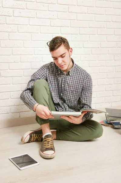 Young man sits with textbooks on the floor
