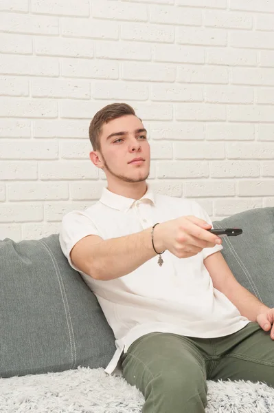 Nastolatek z pilota siedzi na kanapie i zegarki Tv — Zdjęcie stockowe
