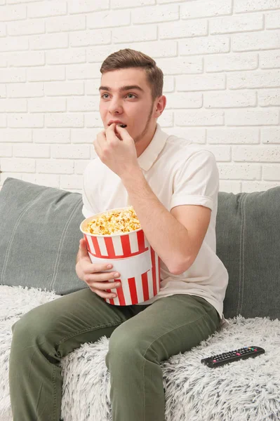 Um adolescente assistindo TV e comendo pipocas — Fotografia de Stock