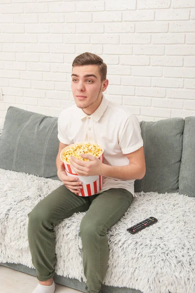 Un adolescente viendo televisión y comiendo palomitas de maíz —  Fotos de Stock