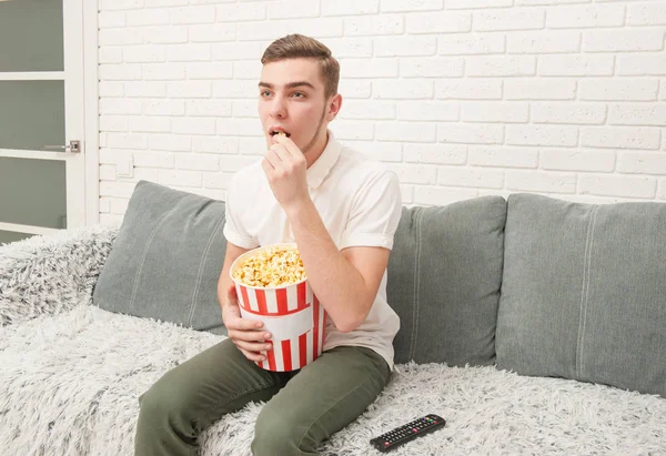 Nastoletni chłopak oglądania telewizji i jedzenie popcorn — Zdjęcie stockowe