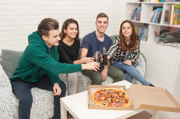 A company of teenagers eating pizza