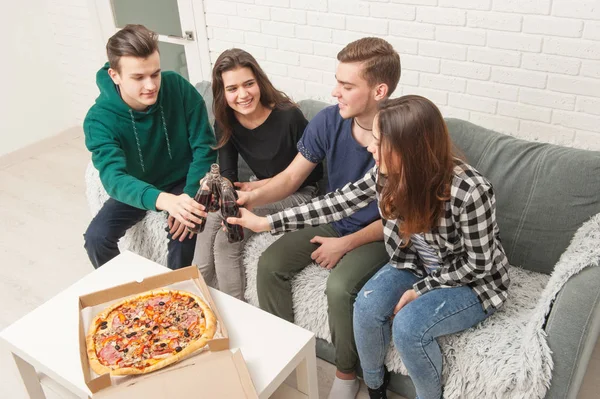 A company of teenagers eating pizza