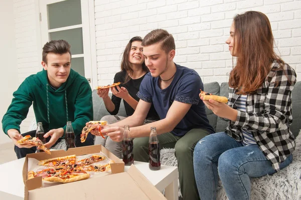 A company of teenagers eating pizza