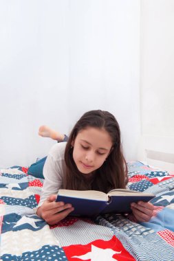 kız yatakta yatıyordu ve bir kitap okuma