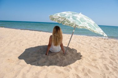 Bir plaj şemsiyesi altında oturan kız