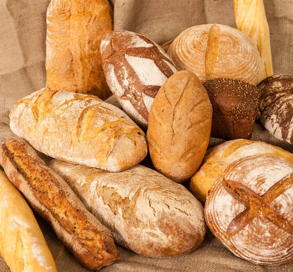 Varios tipos de pan sobre fondo de arpillera —  Fotos de Stock