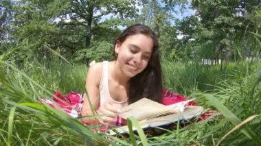 Kız yazın çayırda kitap okur.