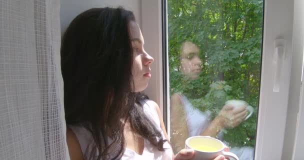 一个喝茶的女孩坐在窗台上 — 图库视频影像