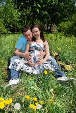 Çayırda hamile bir karısı olan bir adam.