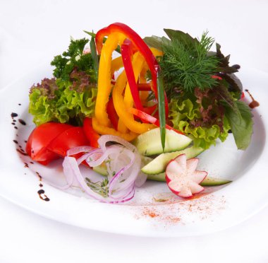 Beyaz arka planda farklı sebzelerle salata.