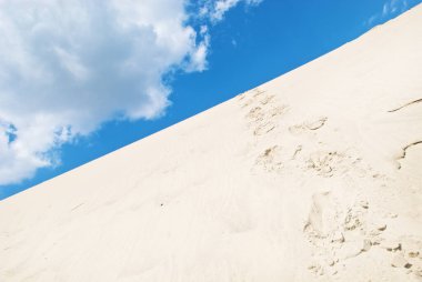 Ayak izleri ve gökyüzü olan kum tepecikleri