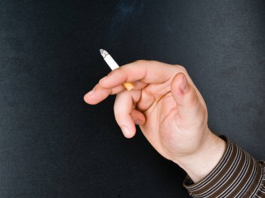 Siyah arka planda erkek parmaklarıyla sigara