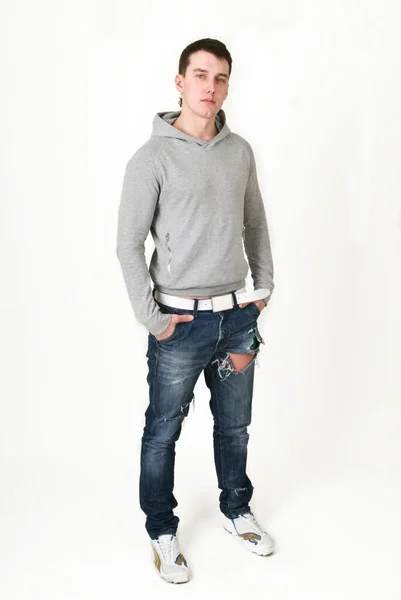 Jongeman in een grijze sweater op een witte achtergrond — Stockfoto
