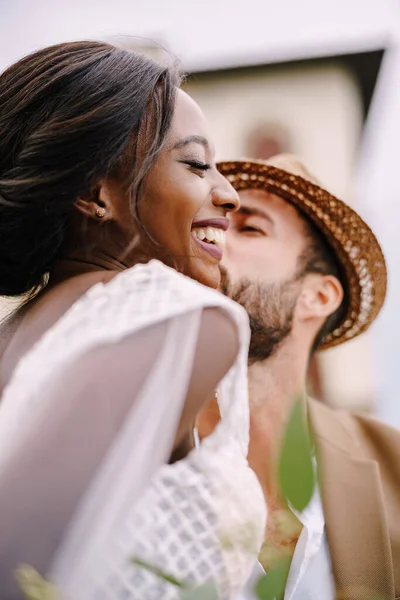 Multiraciaal echtpaar. Bruiloft in Florence, Italië. Een close-up van portretten van een Afro-Amerikaanse bruid en Kaukasische bruidegom in een strohoed. — Stockfoto