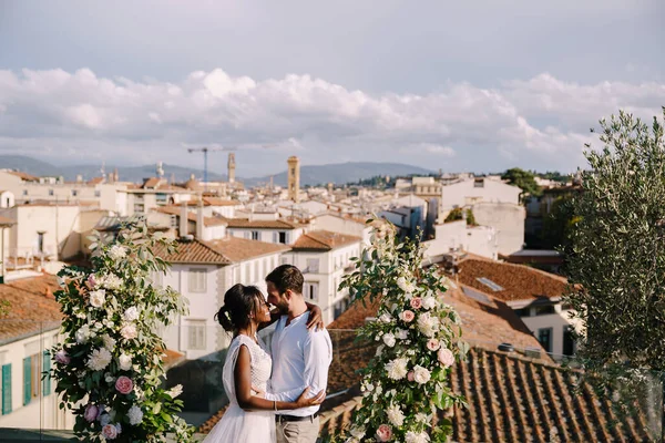 Pasangan pernikahan antar ras. Sebuah upacara pernikahan di atap bangunan, dengan pemandangan kota dan Katedral Santa Maria Del Fiore. Tujuan pernikahan seni rupa di Florence, Italia Stok Gambar