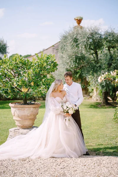 Esküvői pár a kertben. A vőlegény megöleli a menyasszonyt a citromfák mellett. Esküvő Firenzében, Olaszországban, egy régi villa-pincészetben. — Stock Fotó