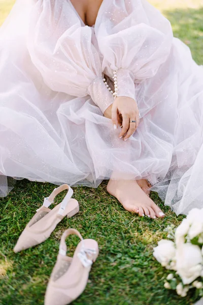 Los pies desnudos de la novia en la hierba, junto a los zapatos y un ramo. Boda en Florencia, Italia, en una antigua villa-bodega . —  Fotos de Stock