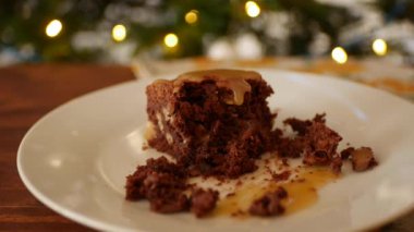 Kız çatallı kare çikolatalı brownie 'yi tabakta yer, tuzlu karamel döker.