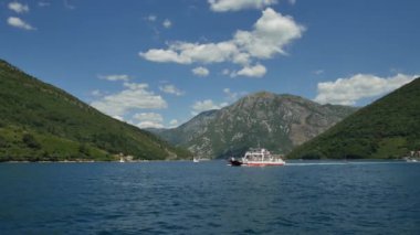 Tivat, Karadağ - 15 Mayıs 2016: Tivat yakınlarındaki Kotor Bay, Lepetane - Kamenari 'den geçen feribot. Deniz feribotu kıyıya, dağların arka planına ve bulutlu mavi gökyüzüne yaklaşıyor..