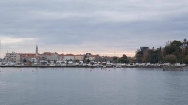 Budva 'daki tekne ve yatlar için rıhtım, eski kasabanın yakınında. Kasvetli bulutlu sonbahar gökyüzü. Şehrin üzerinde kurşun bulutlar asılı.