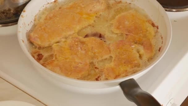 Tritare il milanese fritto in padella. cotoletta fritta in olio di girasole bollente. Carne di pollo tritata. Il processo di cottura su una stufa elettrica a casa . — Video Stock