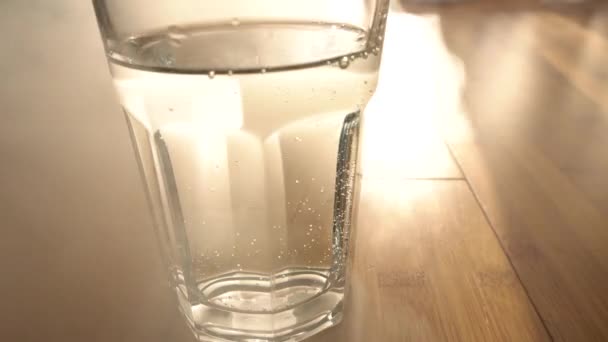 Glass with sparkling clear water, on wooden background. — Stock Video