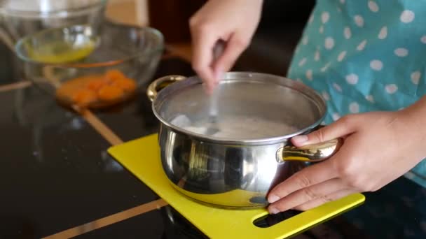 Woman chef pours dry yeast into milk in a pan and stirs with a fork to dissolve. — Stock Video