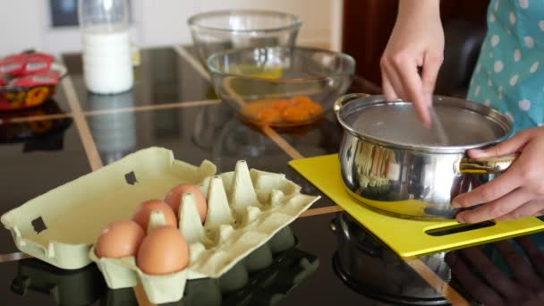 Vrouwelijke chef giet droge gist in melk in een pan en roert met een vork op te lossen. — Stockvideo