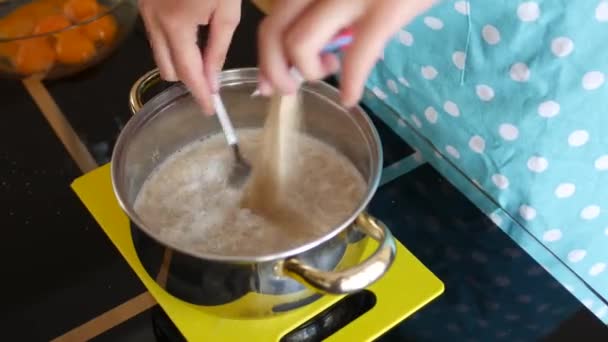 Vrouwelijke chef giet droge gist in melk in een pan en roert met een vork op te lossen. — Stockvideo