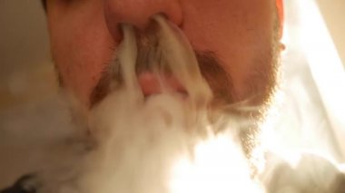 Elektronik sigara içen sakallı adam. Vaper. Sigara dumanı oluşturmuş. Geleceğin sigara tiryakisi kavramı, elektronik sigaraların yol açtığı sağlık sorunları veya hastalıklarla ilgilenmek