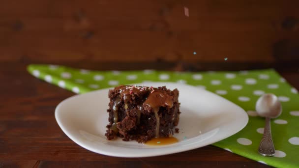 En fyrkantig bit choklad Brownie på en platta, beströdd med flerfärgat socker pulver. — Stockvideo