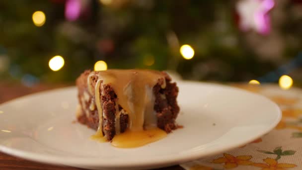 Un morceau carré de Brownie au chocolat sur une assiette, du caramel doré salé s'égoutte . — Video