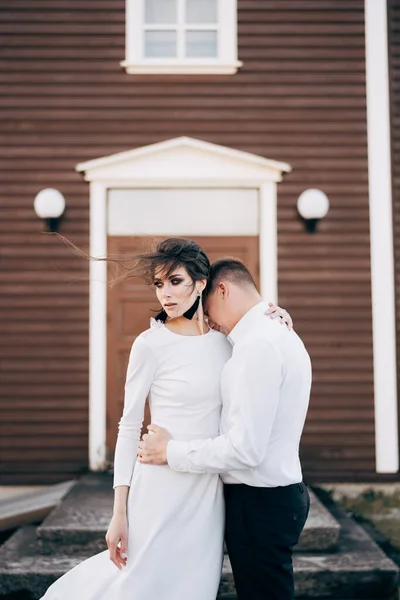 Mariage Destination Islande. Couple de mariage devant une église noire. Le marié embrasse la mariée . — Photo