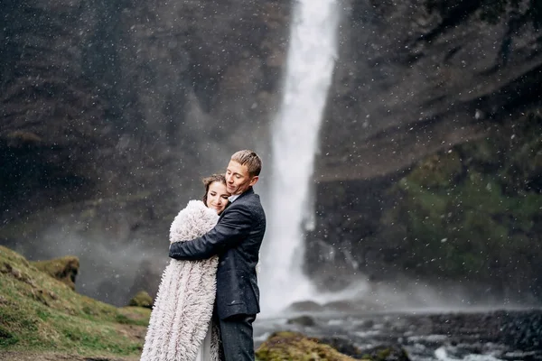 Mariage Destination Islande, près de la cascade de Kvernufoss. Couple de mariage est debout près de la cascade. Le marié embrasse la mariée . — Photo