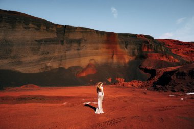 Kız arkası dönük duruyor. Altın bir gelinlik içinde bir gelin modeli portresi, sarı-kırmızı bir taş ocağında, İzlanda 'da bir volkanın kraterinde, Altın Çember.