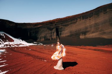Kız battaniye sallıyor. Altın bir gelinlik içinde bir gelin modeli portresi, sarı-kırmızı bir taş ocağında, İzlanda 'da bir volkanın kraterinde, Altın Çember.