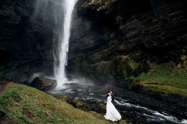 Mariage Destination Islande, près de la cascade de Kvernufoss. Couple de mariage est debout près de la cascade. Le marié embrasse la mariée . — Photo