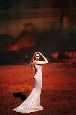 Sert ışık, kız elini yüzüne tutuyor. Altın bir gelinlik içinde bir gelin modeli portresi, sarı-kırmızı bir taş ocağında, İzlanda 'da bir volkanın kraterinde, Altın Çember.