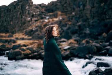 Ehsaraurfoss Şelalesi, Ehsarau Nehri, Ulusal Park, Tingwedlir, Sudurland bölgesi yakınlarında kırmızı elbiseli bir kız..