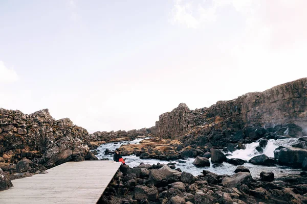 Хлопець і дівчинка сидять в обіймах на мосту поблизу Ехсараурфосс Вотерфолл, ріка Ехсарау, національний парк, Тінґведлір, в районі Судурланд, Ісландія.. — стокове фото
