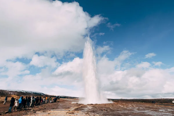 Geyser Valley in the southwest of Iceland. The famous tourist attraction Geysir. Geothermal zone Haukadalur. Tourists look at the eruption of Strokkur geyser on the slopes of Laugarfjall hill. — Stock Photo, Image