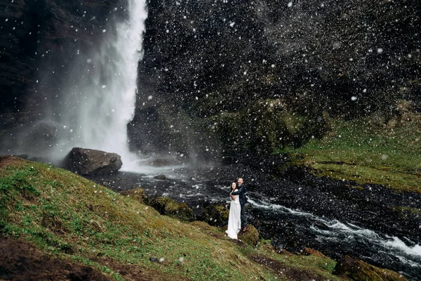 Kvernufoss 폭포 근처에서 열리는 아이슬란드 결혼식입니다. 결혼 한 커플 이 폭포 근처에 서 있습니다. 신랑은 신부를 껴 안 는다. — 스톡 사진