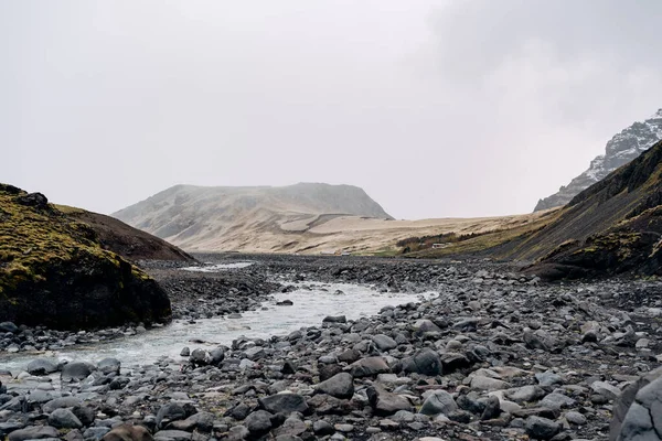 Felsiger flacher Gebirgsfluss in Island, der vor der Kulisse der Berge fließt. — Stockfoto