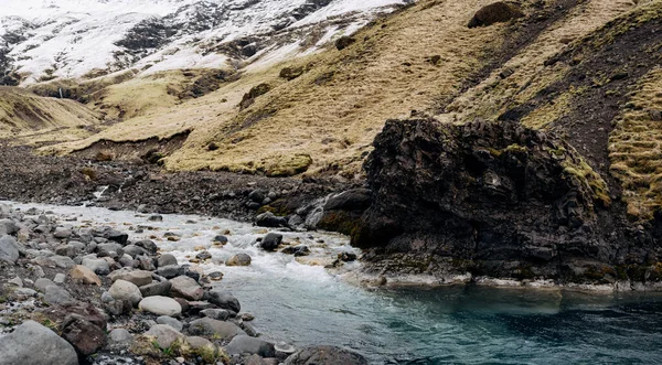 Ένα ρηχό ορεινό ποτάμι με μπλε γαλαζοπράσινα νερά ρέει στο φόντο των βουνών στις mth και χιονισμένες κορυφές. — Φωτογραφία Αρχείου