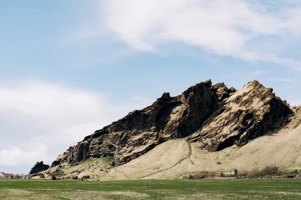 푸른 초원, 풀로 소를 기르는 밭, 아이슬란드의 바위투성이 산들 과푸른 하늘을 배경으로 하는 푸른 하늘. — 스톡 사진