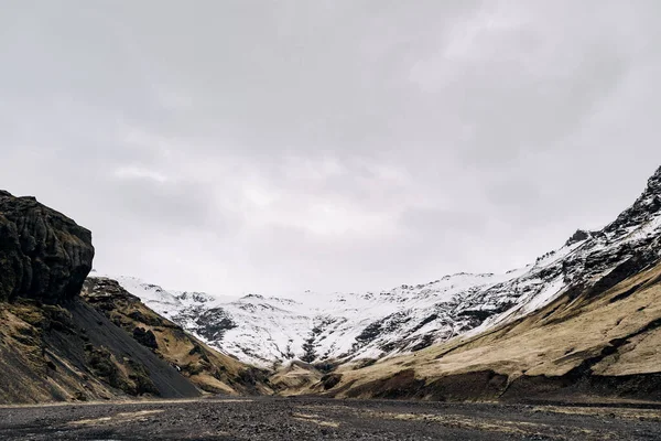 Ущелина гори вкрита снігом, сухим жовтим травою у передгір "ях гори в Ісландії.. — стокове фото