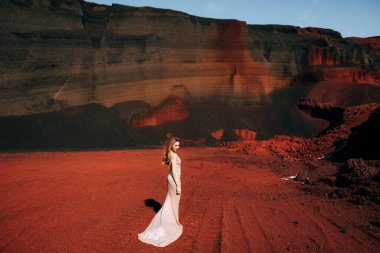 Kız arkası dönük duruyor. Altın bir gelinlik içinde bir gelin modeli portresi, sarı-kırmızı bir taş ocağında, İzlanda 'da bir volkanın kraterinde, Altın Çember.