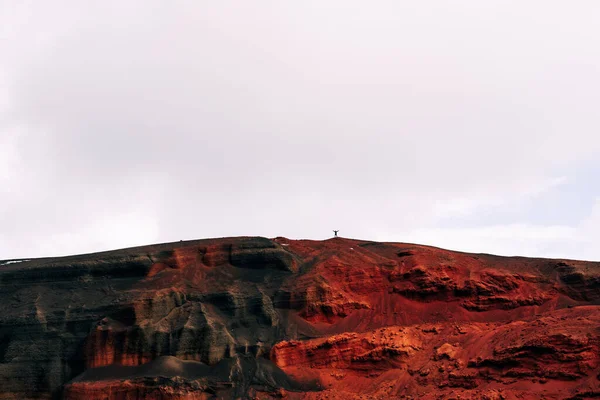 아이슬란드의 화성 경관. 세이디 쇼어 화산의 붉은 분화구. 붉은 토양 광산의 채석장. 붉은 검은 산 꼭대기에 있는 한 남자의 실루엣. — 스톡 사진